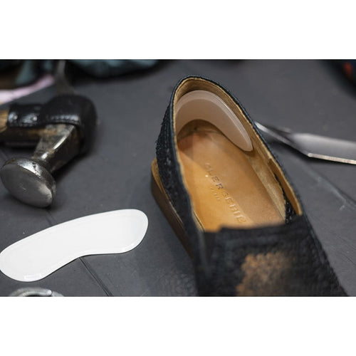 Antiglissoir en gel transparent collé contre le contrefort d’une chaussure noire.
