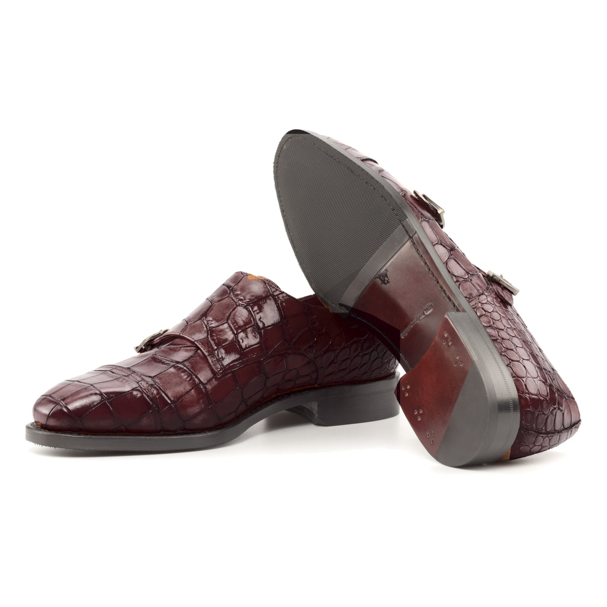 Chaussure double boucle en cuir croco bordeaux : une chaussure debout, l’autre couchée montre sa semelle