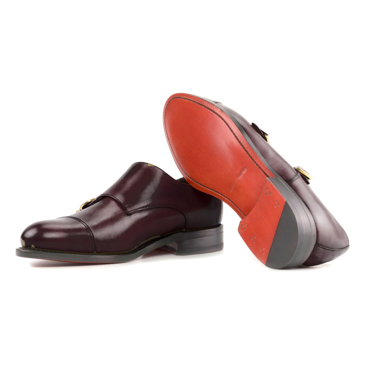 Chaussure double boucle en cuir teinté main bordeaux : une chaussure debout, l’autre couchée montre sa semelle