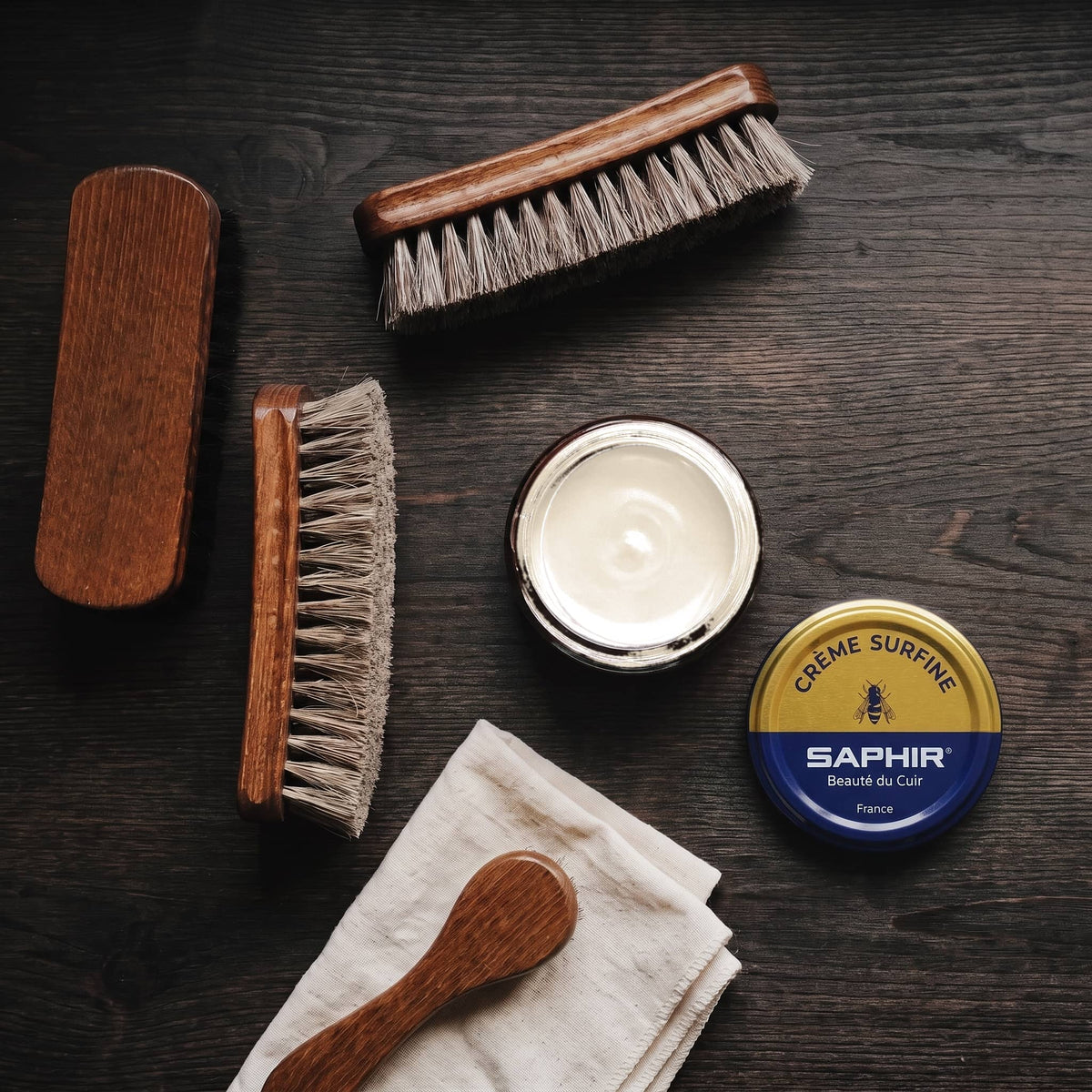 Crème Surfine Saphir Beige rosé en pot ouvert, avec des brosses en crin et une chamoisine, vue de dessus