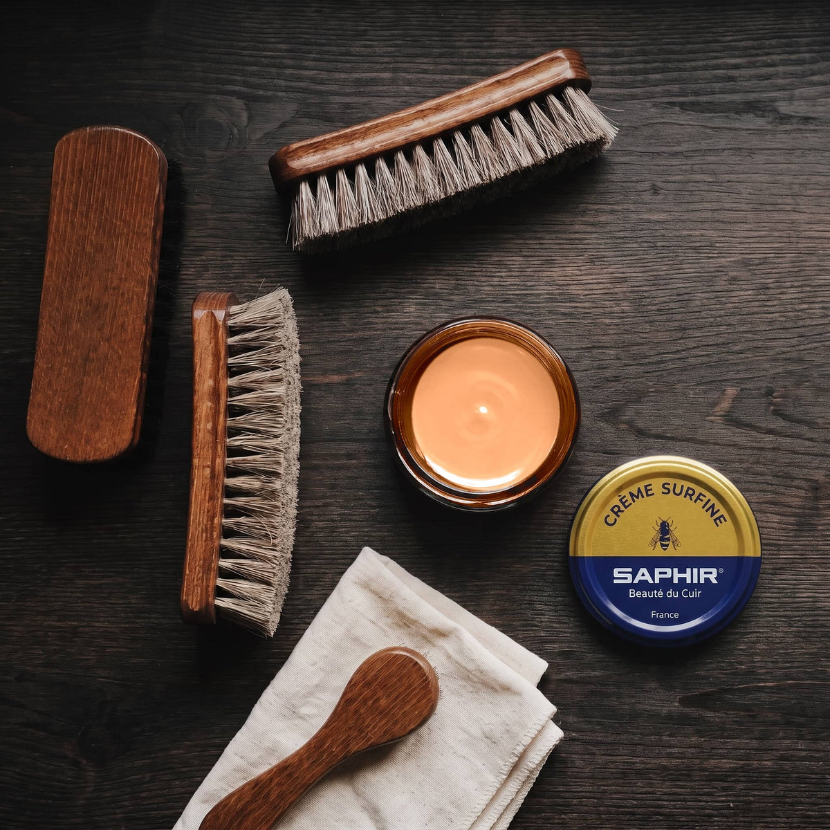 Crème Surfine Saphir Pêche en pot ouvert, avec des brosses en crin et une chamoisine, vue de dessus