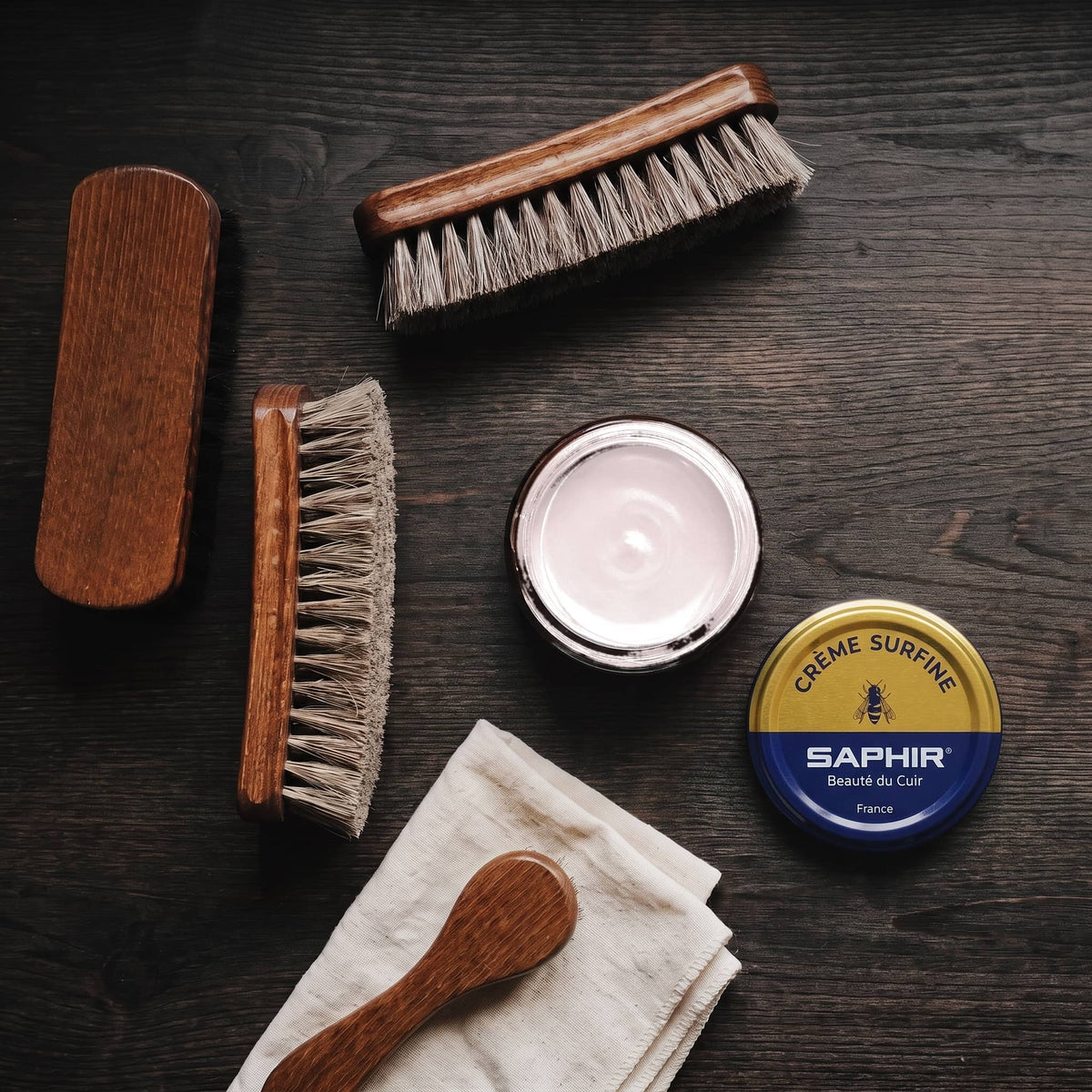 Crème Surfine Saphir Rose pâle en pot ouvert, avec des brosses en crin et une chamoisine, vue de dessus