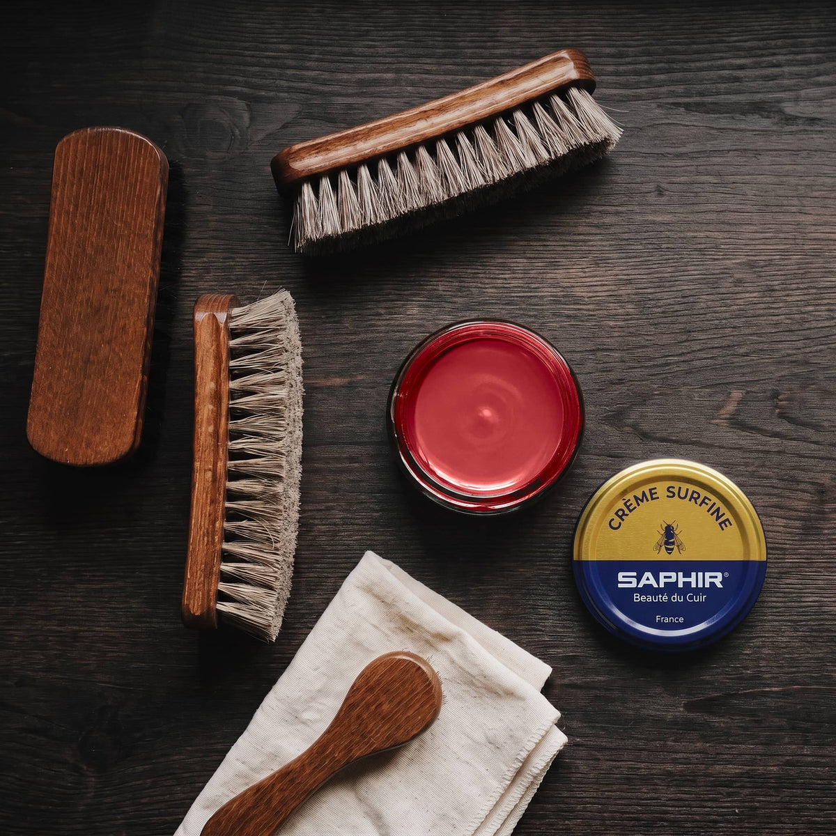 Crème Surfine Saphir Rouge cerise en pot ouvert, avec des brosses en crin et une chamoisine, vue de dessus