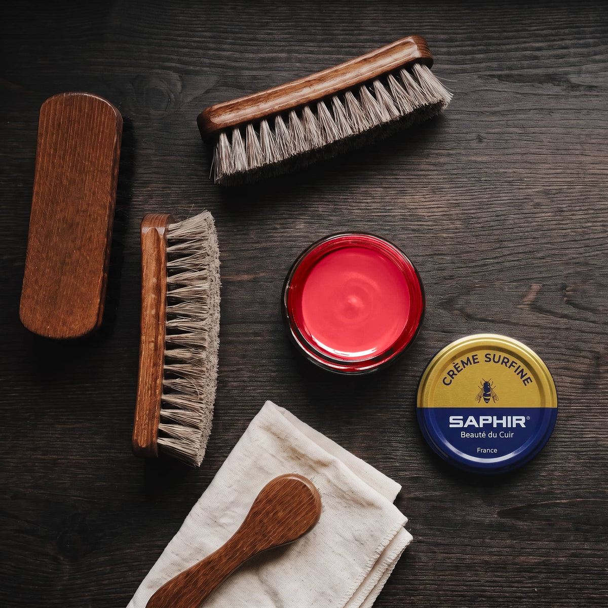 Crème Surfine Saphir Rubis en pot ouvert, avec des brosses en crin et une chamoisine, vue de dessus