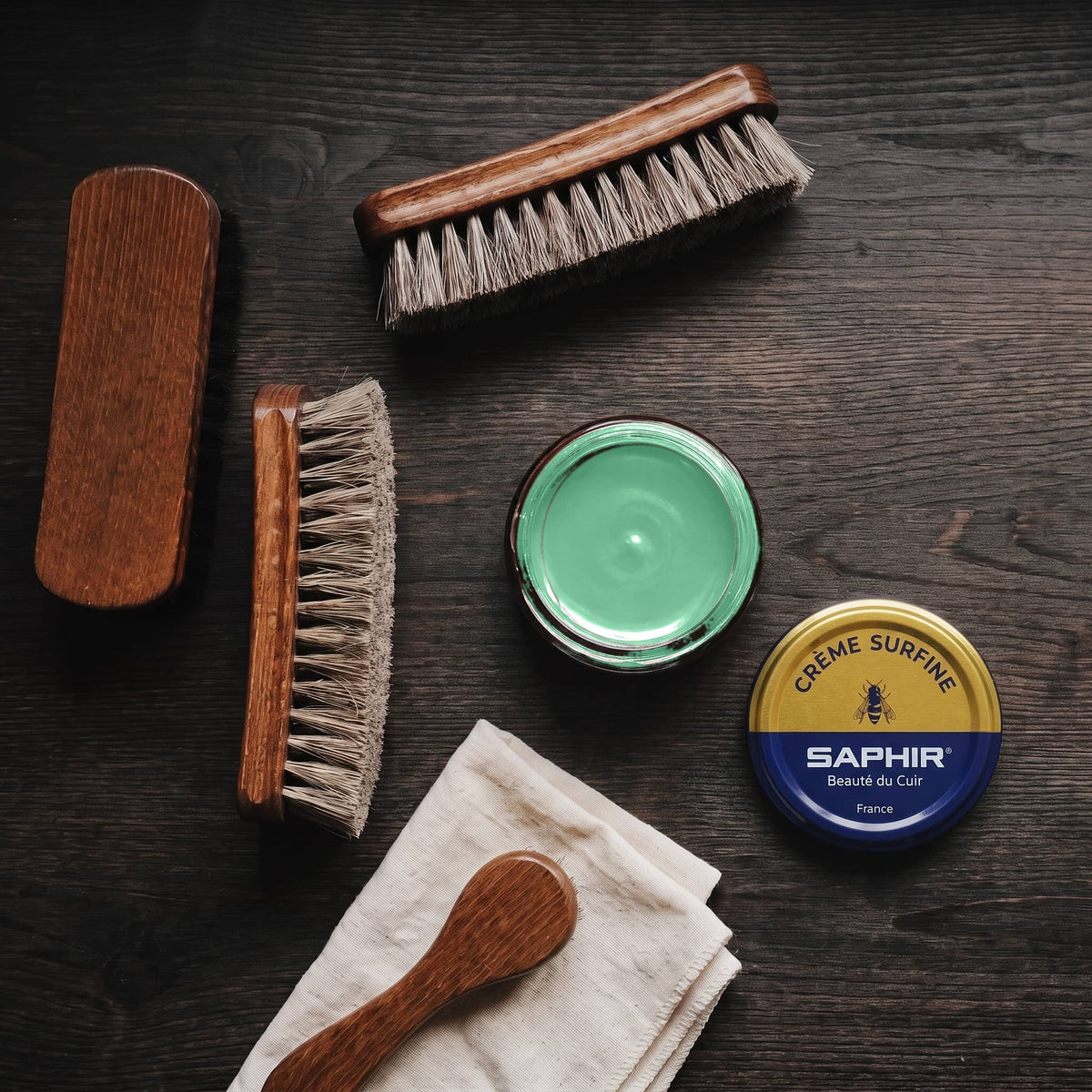Crème Surfine Saphir Vert jardin en pot ouvert, avec des brosses en crin et une chamoisine, vue de dessus