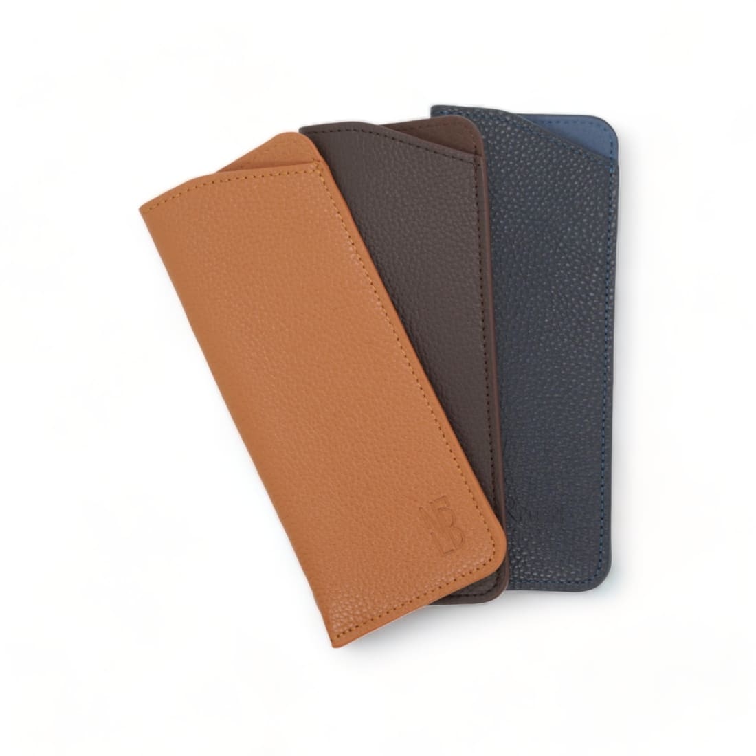 Les trois étuis à lunettes en cuir grainé debout, en éventail : gold, marron foncé et bleu marine