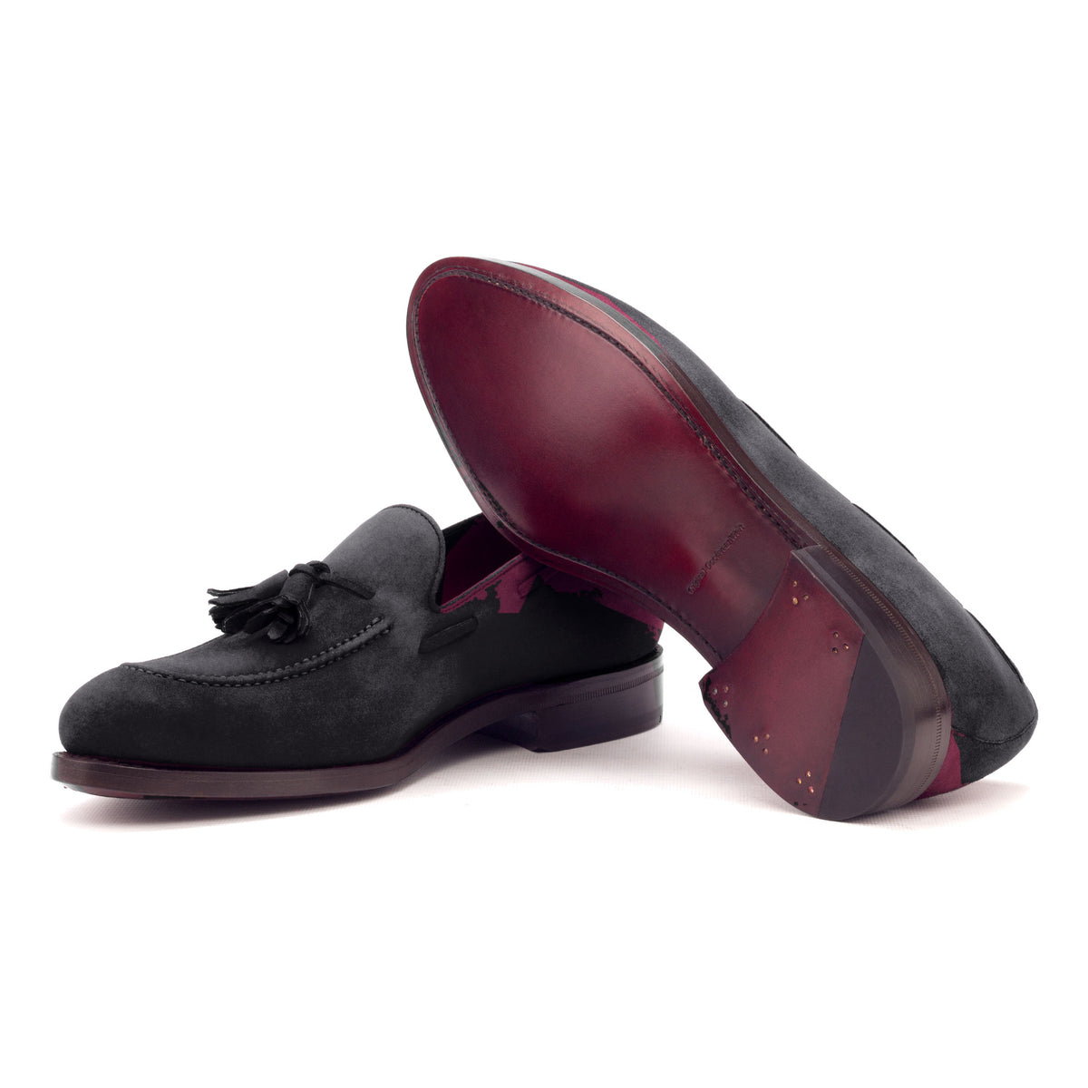 Mocassin à glands en daim noir : une chaussure couchée montre la semelle