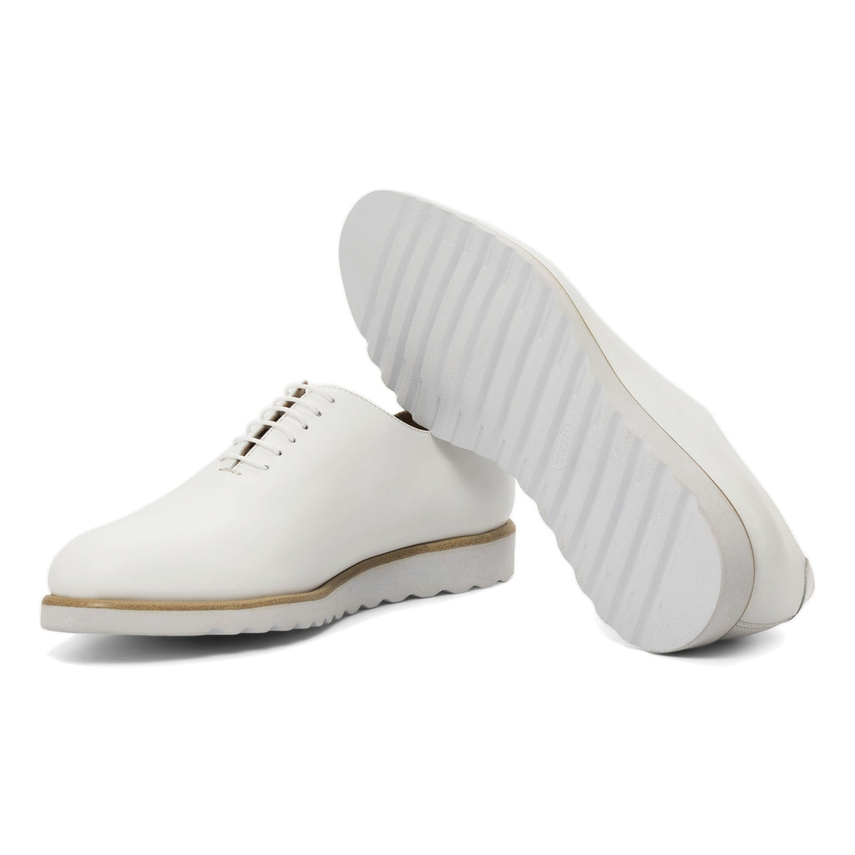 One Cut en cuir blanc : une chaussure debout, l’autre couchée montre sa semelle