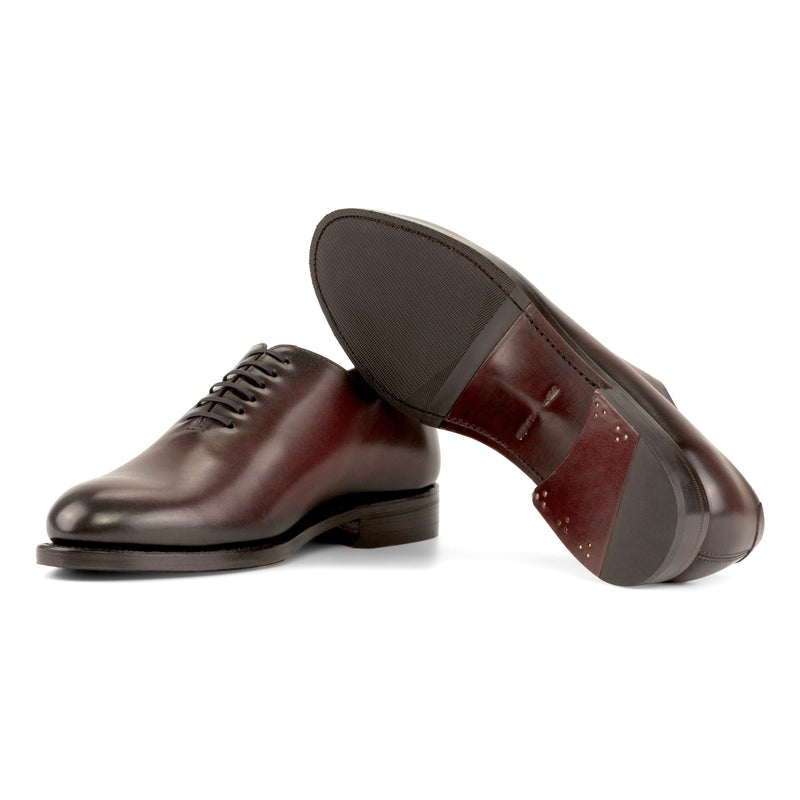 One Cut en cuir bordeaux, semelle cuir avec patin caoutchouc : une chaussure debout, l’autre couchée qui montre sa semelle