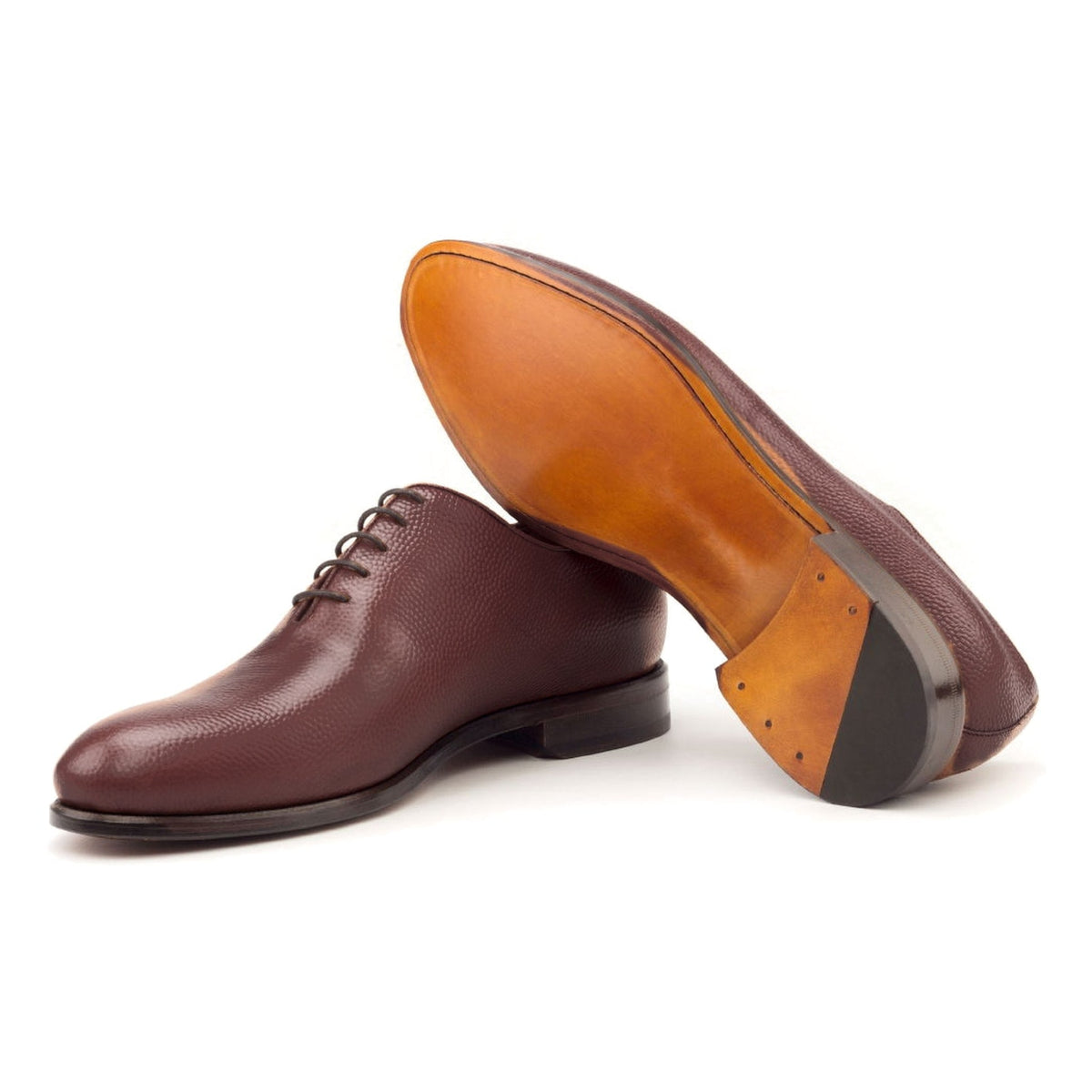 One Cut en cuir gros grain bordeaux, semelle cuir : une chaussure debout, l’autre couchée montre sa semelle