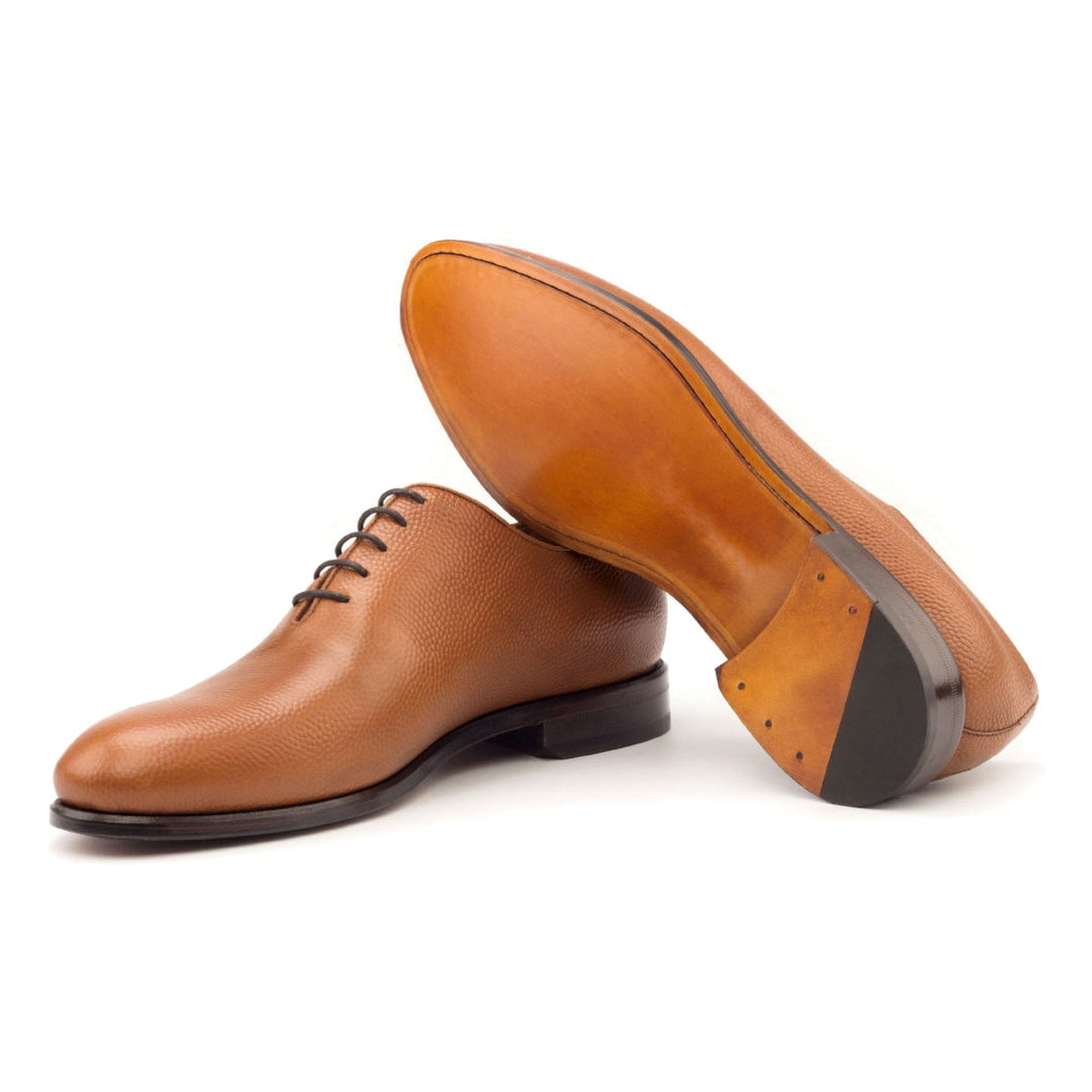 One Cut en cuir gros grain cognac, semelle cuir : une chaussure debout, l’autre couchée montre sa semelle