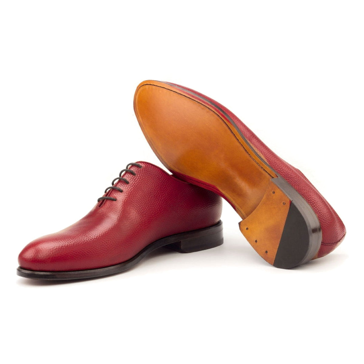 One Cut en cuir gros grain rouge, semelle cuir : une chaussure debout, l’autre couchée montre sa semelle