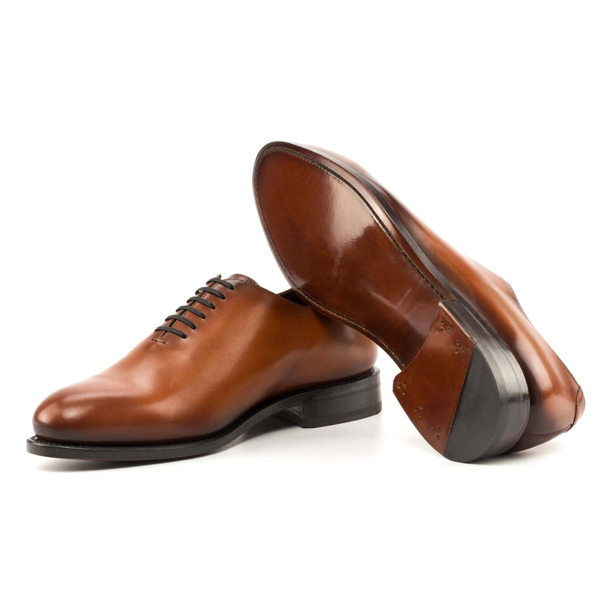 One Cut en cuir teinté main cognac, semelle cuir : une chaussure debout, l’autre couchée montre sa semelle