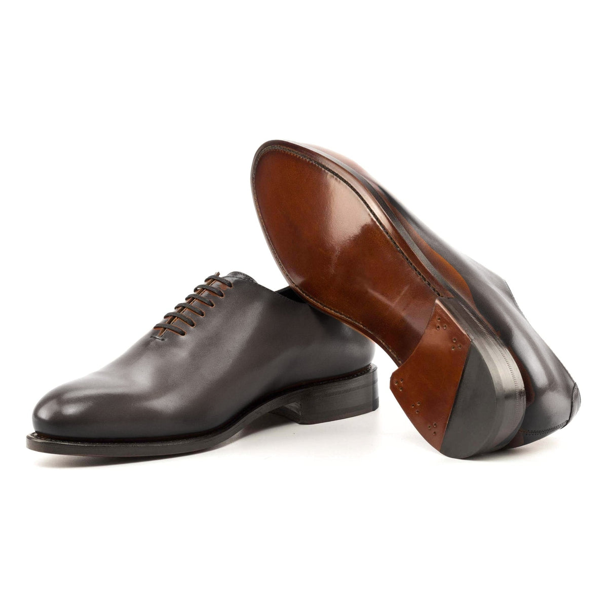 One Cut en cuir teinté main gris, semelle cuir : une chaussure debout, l’autre couchée montre sa semelle