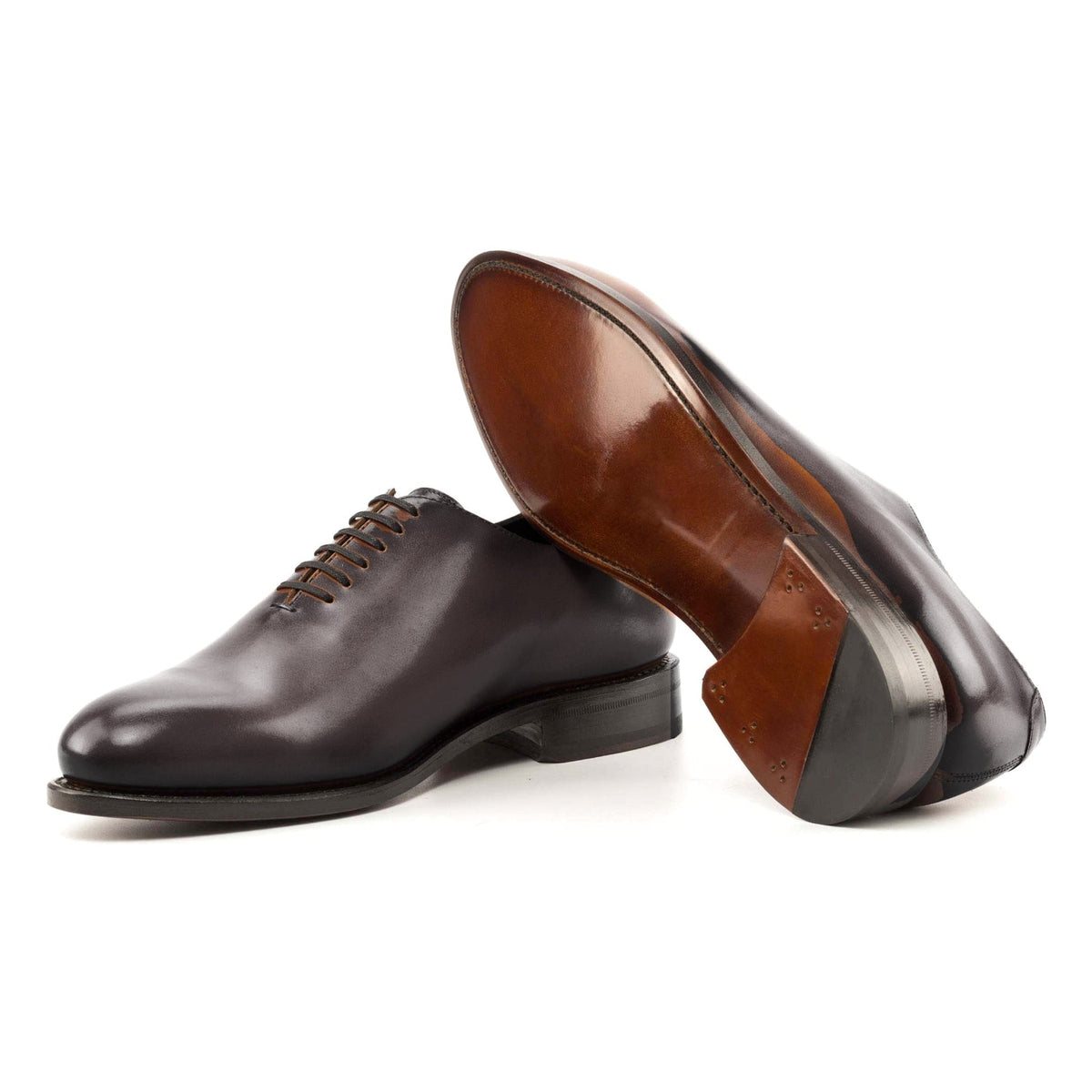 One Cut en cuir teinté main marron foncé, semelle cuir : une chaussure debout, l’autre couchée montre sa semelle