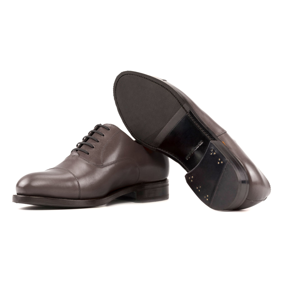 Richelieu bout droit en cuir marron foncé, semelle cuir et patin : une chaussure debout, l’autre couchée montre sa semelle