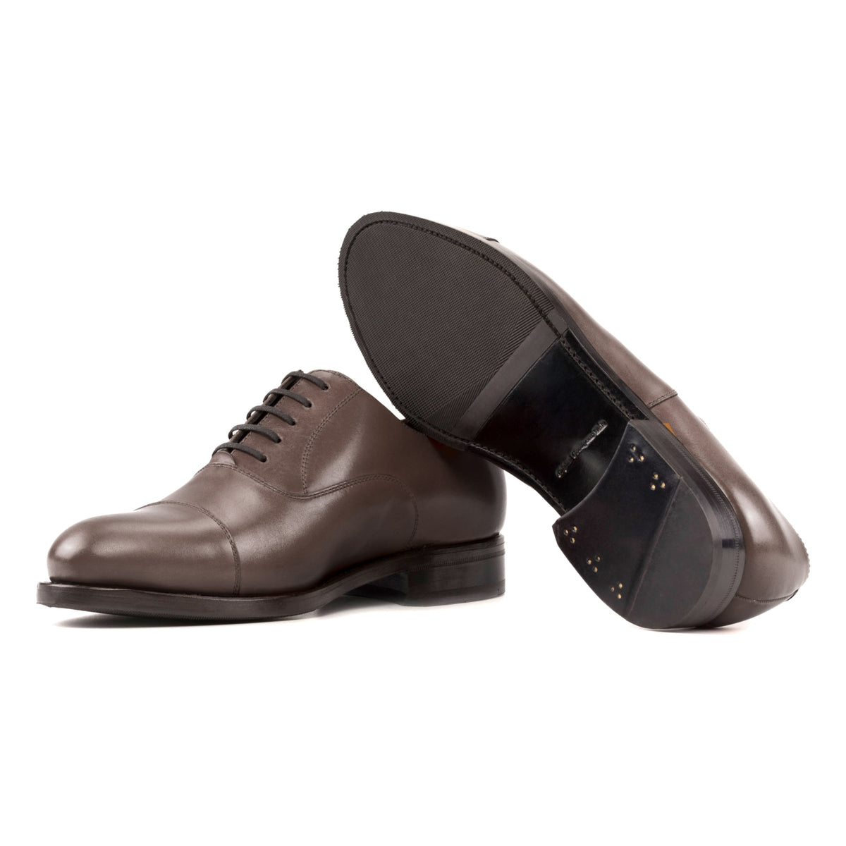 Richelieu bout droit en cuir marron moyen, semelle cuir et patin : une chaussure debout, l’autre couchée montre sa semelle
