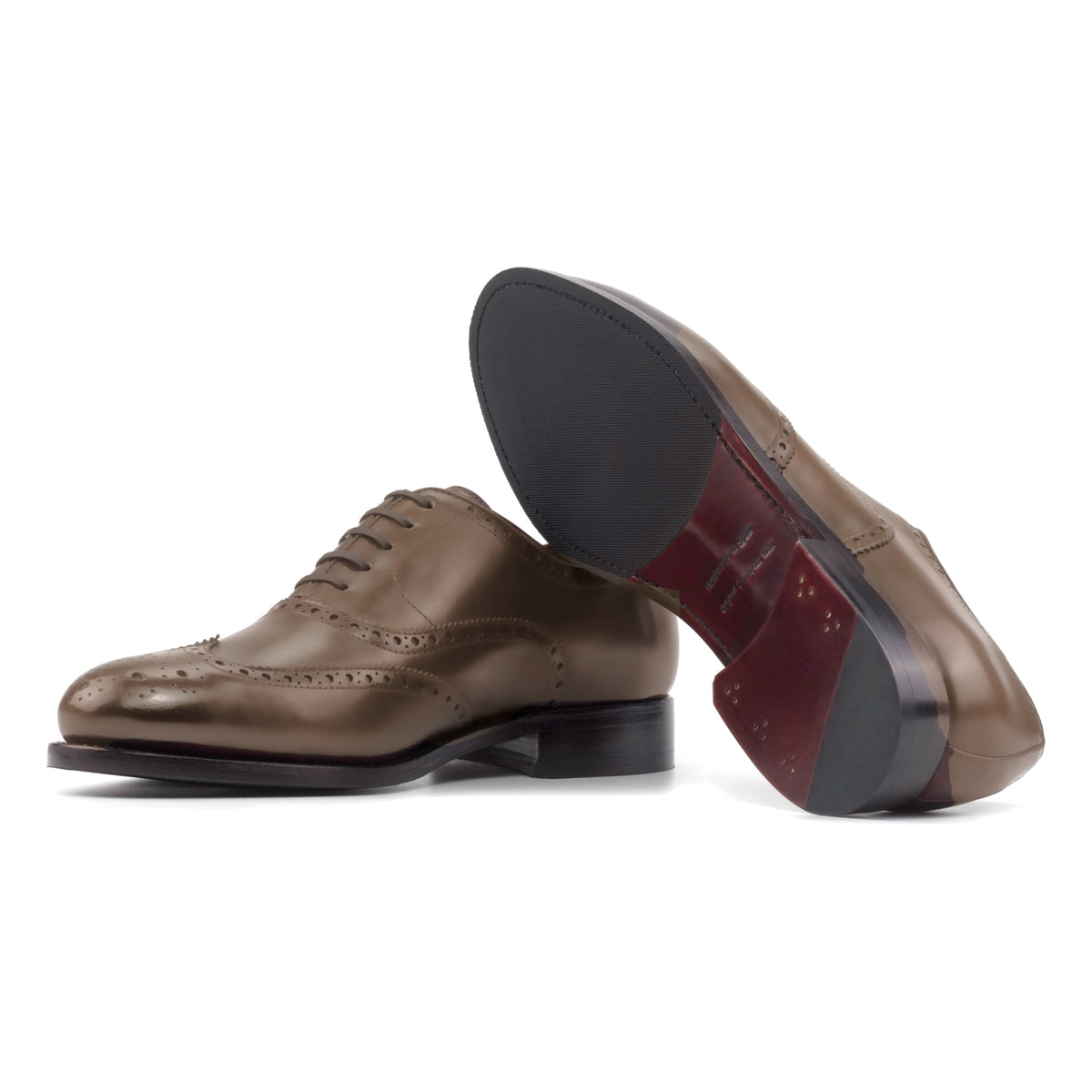 Richelieu fleuri en cuir noisette, semelle cuir et patin : une chaussure debout, l’autre couchée montre sa semelle