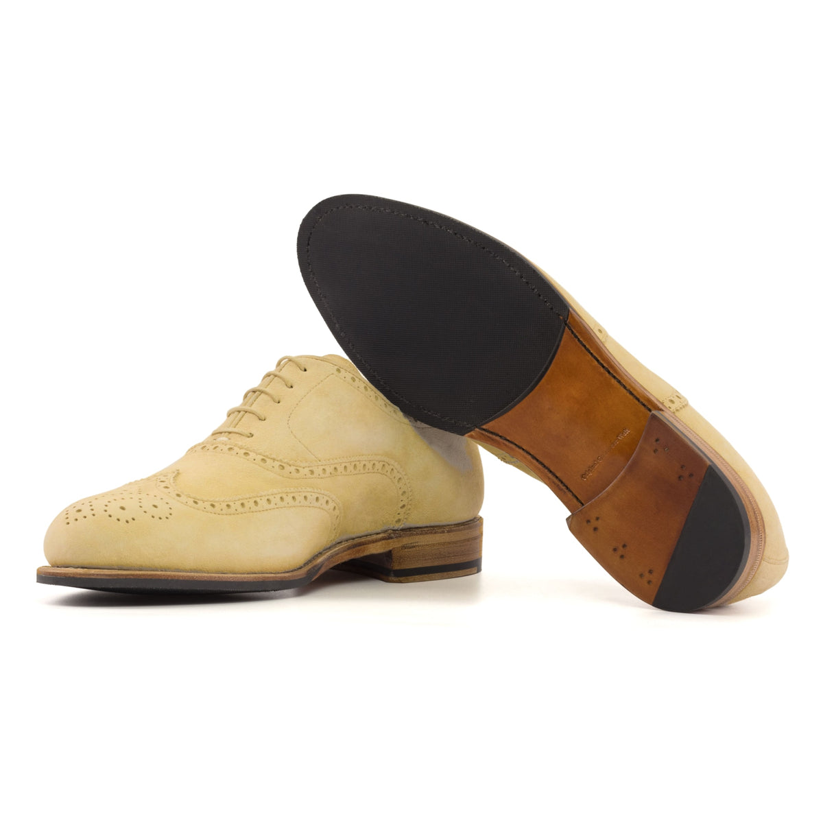 Richelieu fleuri en daim sable, semelle cuir et patin : une chaussure debout, l’autre couchée montre sa semelle